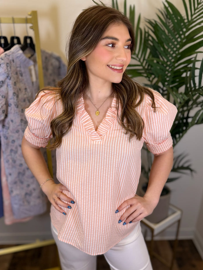 Woman wearing a pink striped blouse in a clothing store setting
