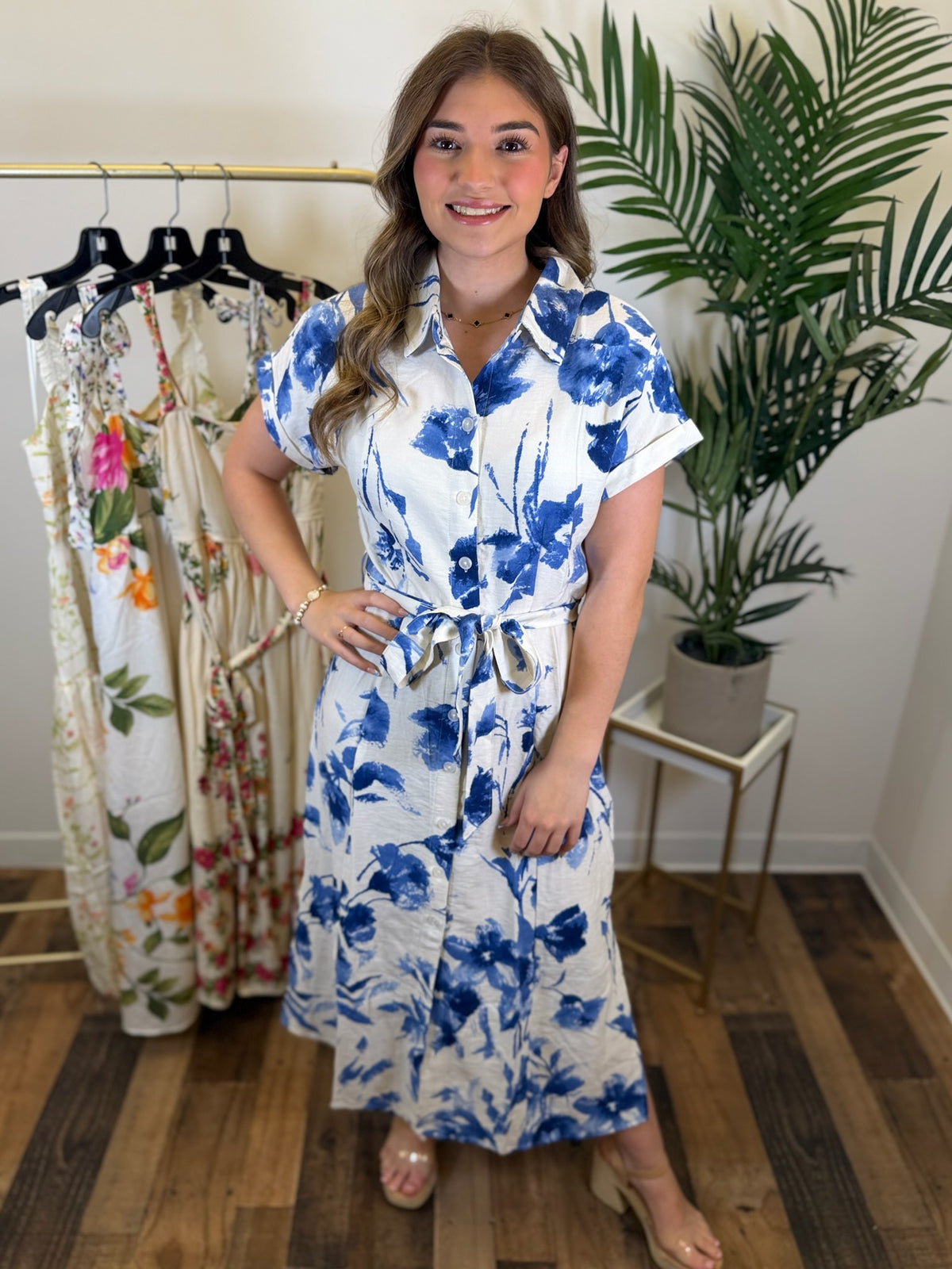 Woman wearing a short sleeve blue floral midi dress in a clothing store.