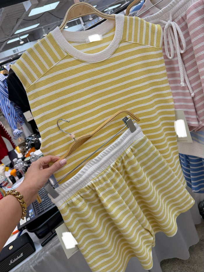 Yellow and white striped top and shorts on a hanger in a store setting