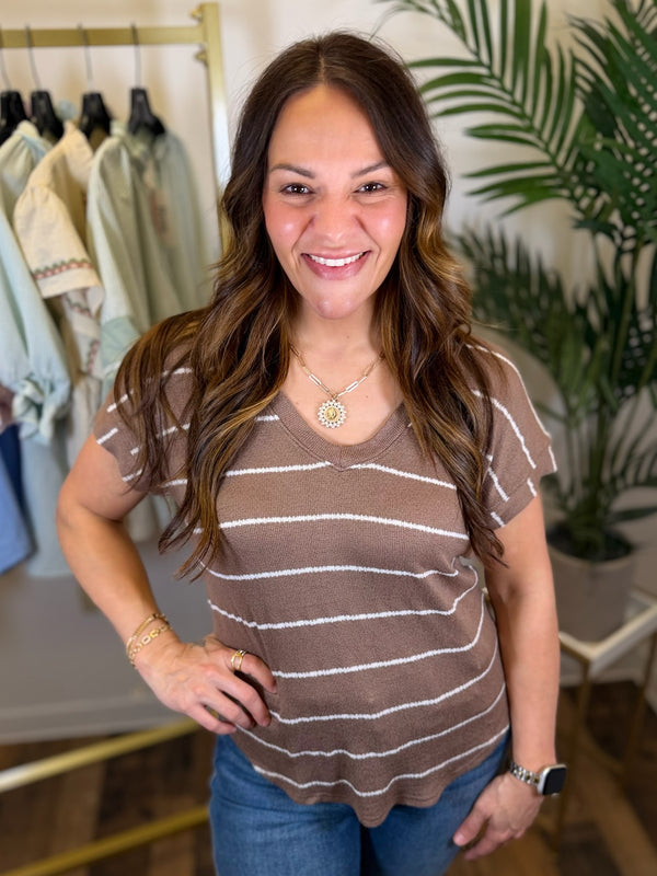 Woman wearing a brown striped shirt in a clothing store setting