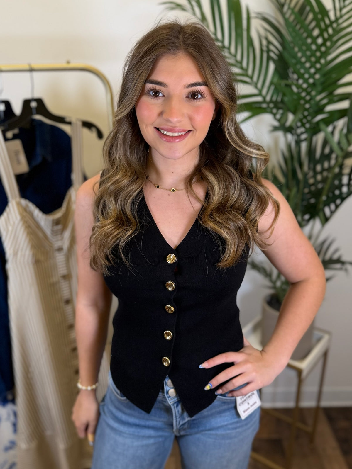 Woman wearing a black button-up vest top and blue jeans in a clothing store.