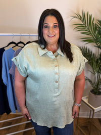 Woman wearing a light green polo shirt standing in a clothing store.
