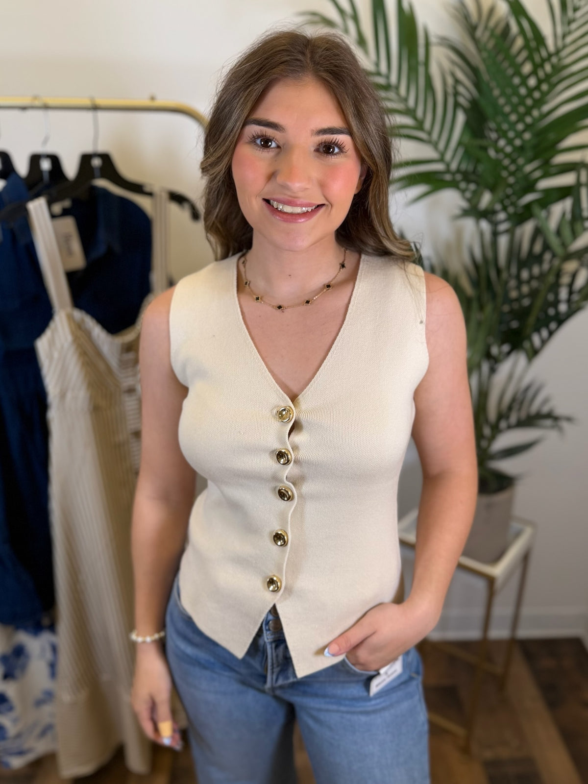 Woman wearing a cream-colored vest with buttons, standing in a clothing store.