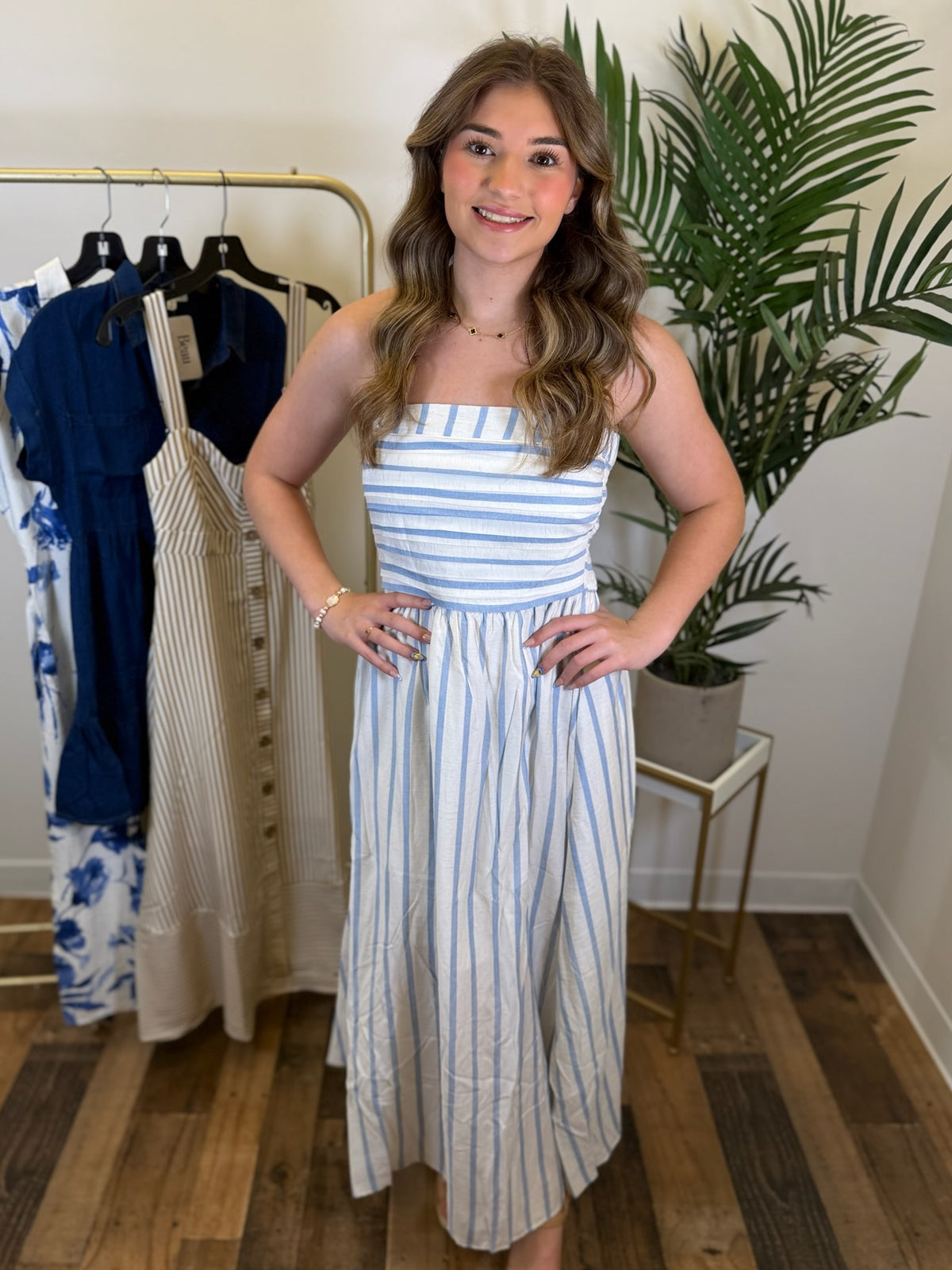 Woman wearing a blue and white striped midi dress in a clothing store.