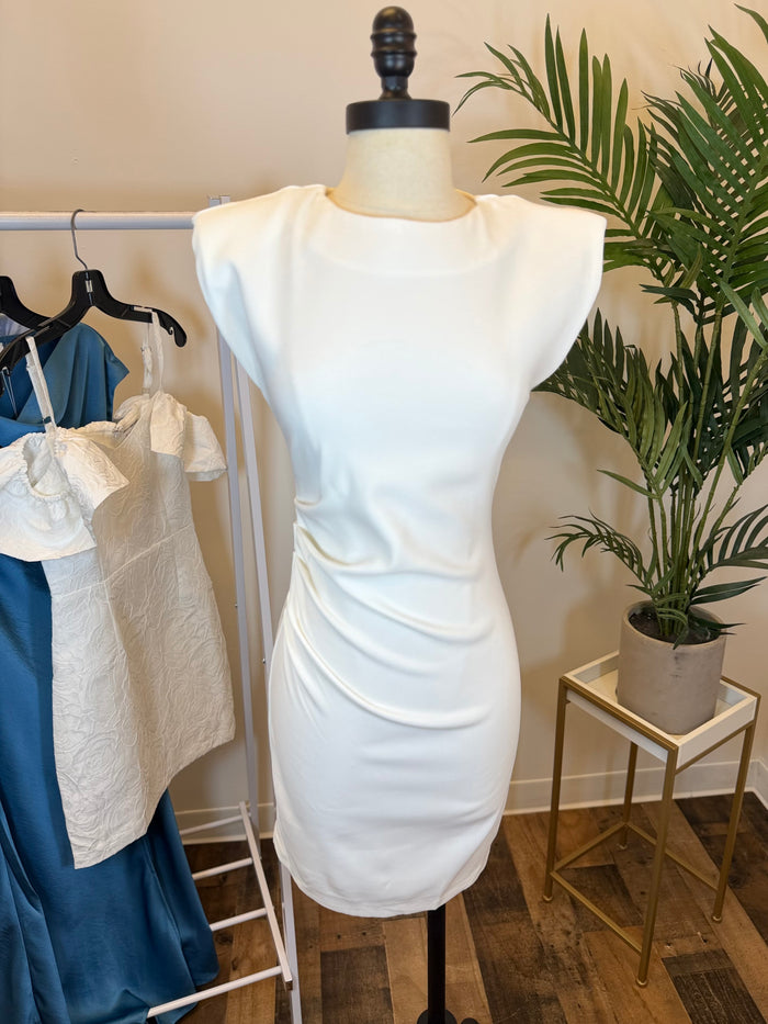 White mini dress with side ruching on a mannequin with a plant and clothing in the background