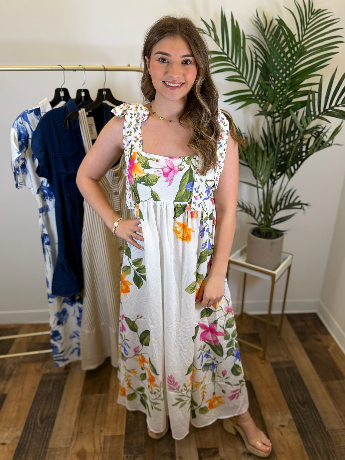 Woman wearing a floral dress in a clothing store with plants in the background