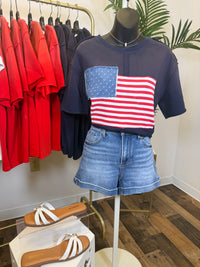 Navy blue vintage wash t-shirt with American flag design on a mannequin, surrounded by colorful shirts on hangers.