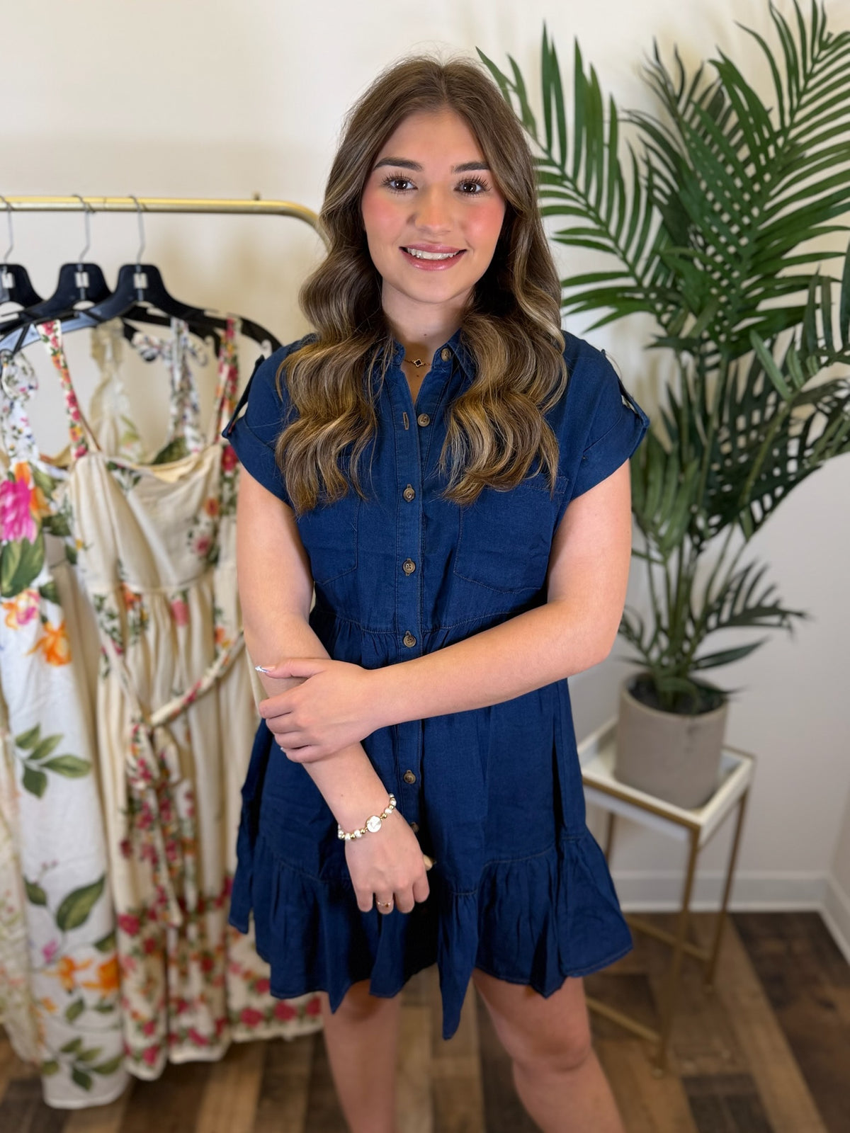 Woman wearing a blue dress standing in a clothing store with plants in the background